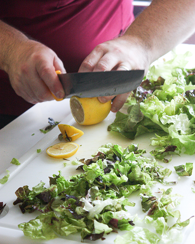 un chef en cuisine en train de couper un citron. On ne voit pas le visage seulement l'action. photographie culinaire à cholet, nantes et angers